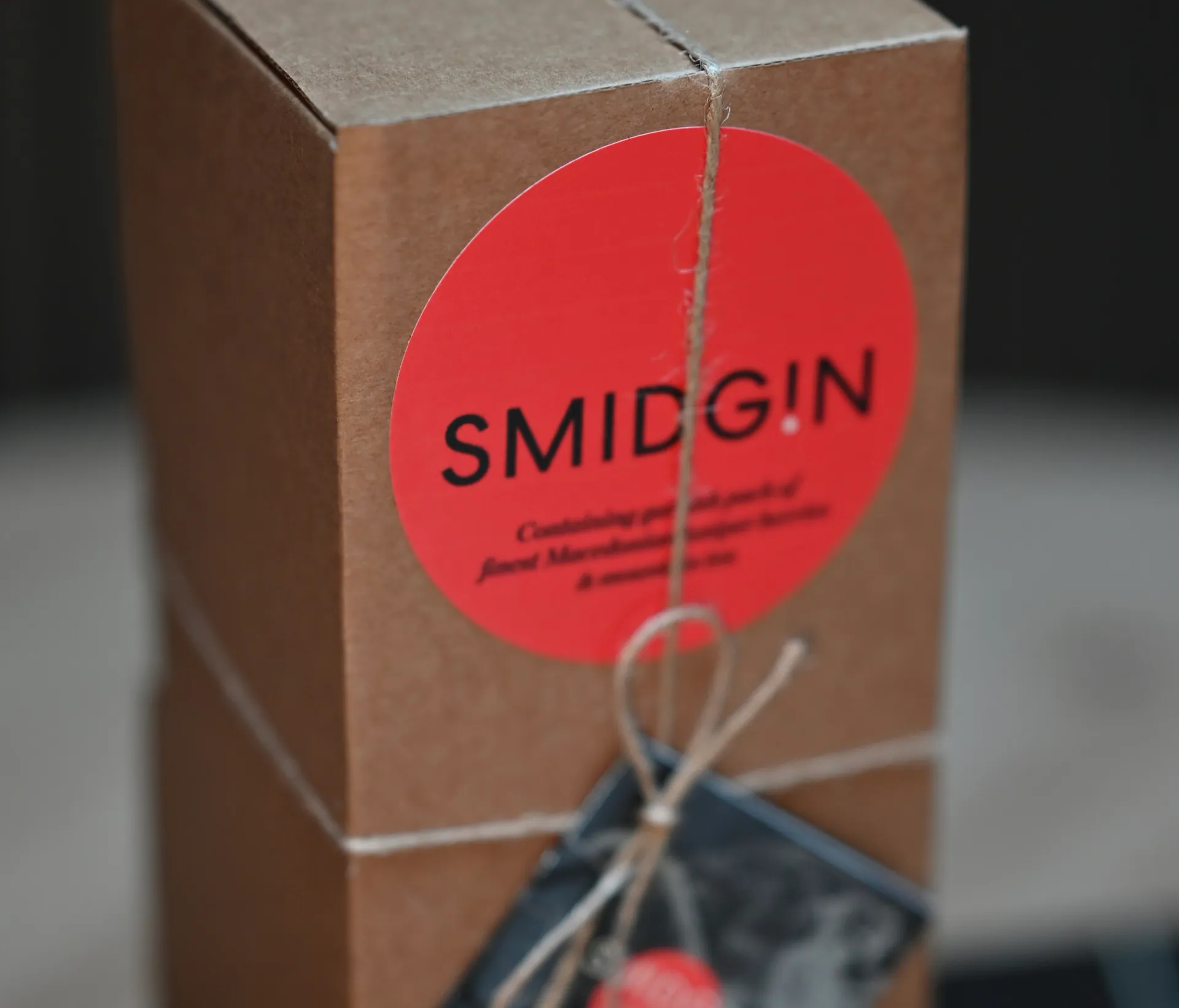 A Smidgin gift box in kraft card, closed with twine and a coral Smidgin seal